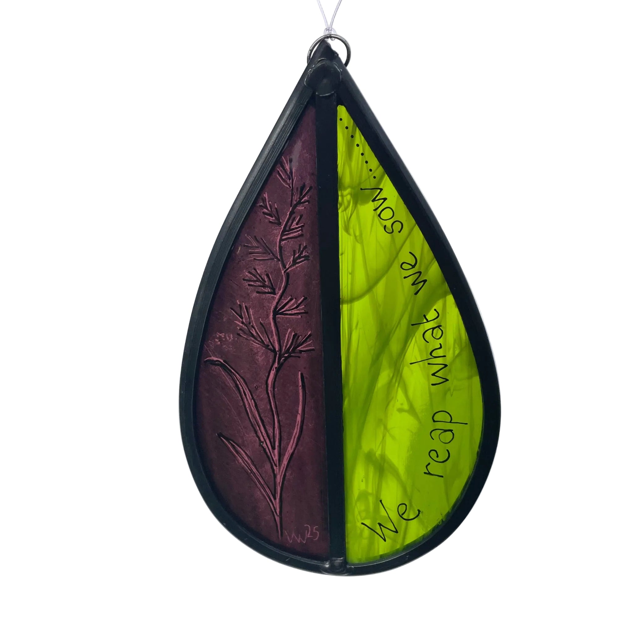 Teardrop-shaped stained glass garden tree spinner, or window sun catcher, with hand painted 'we reap what we sow' and hand drawn  design with of wheat flower,  hanging against a white back ground.