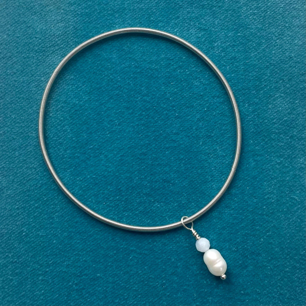 silver wire, elasticated bracelet, with pearl and aquamarine charm, on teal background