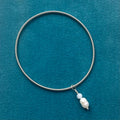 silver wire, elasticated bracelet, with pearl and aquamarine charm, on teal background