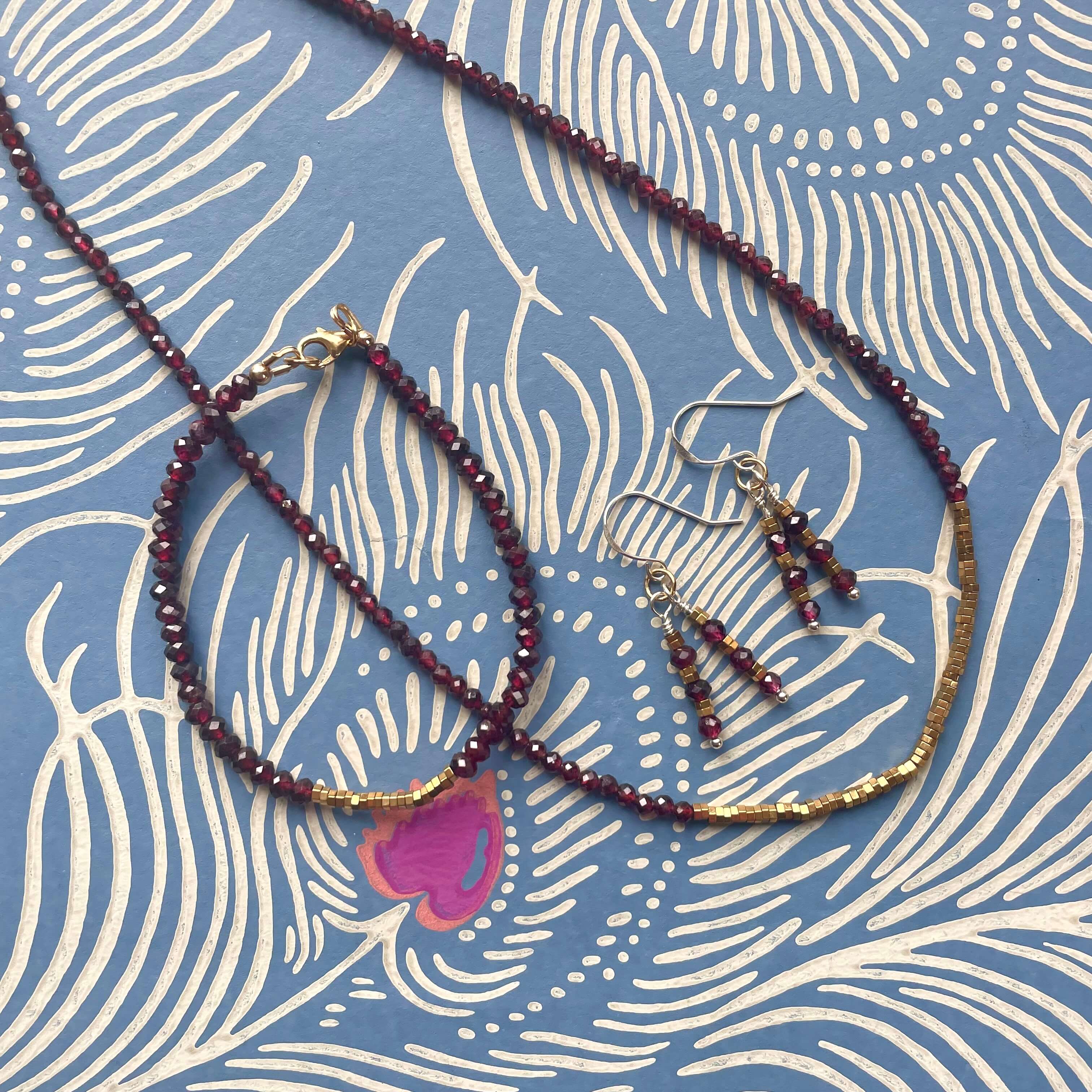 garnet and hematite necklace, bracelet and earrings set, with quality 14k rolled gold fixings and sterling silver ear hooks,  on blue peacock patterned material  background