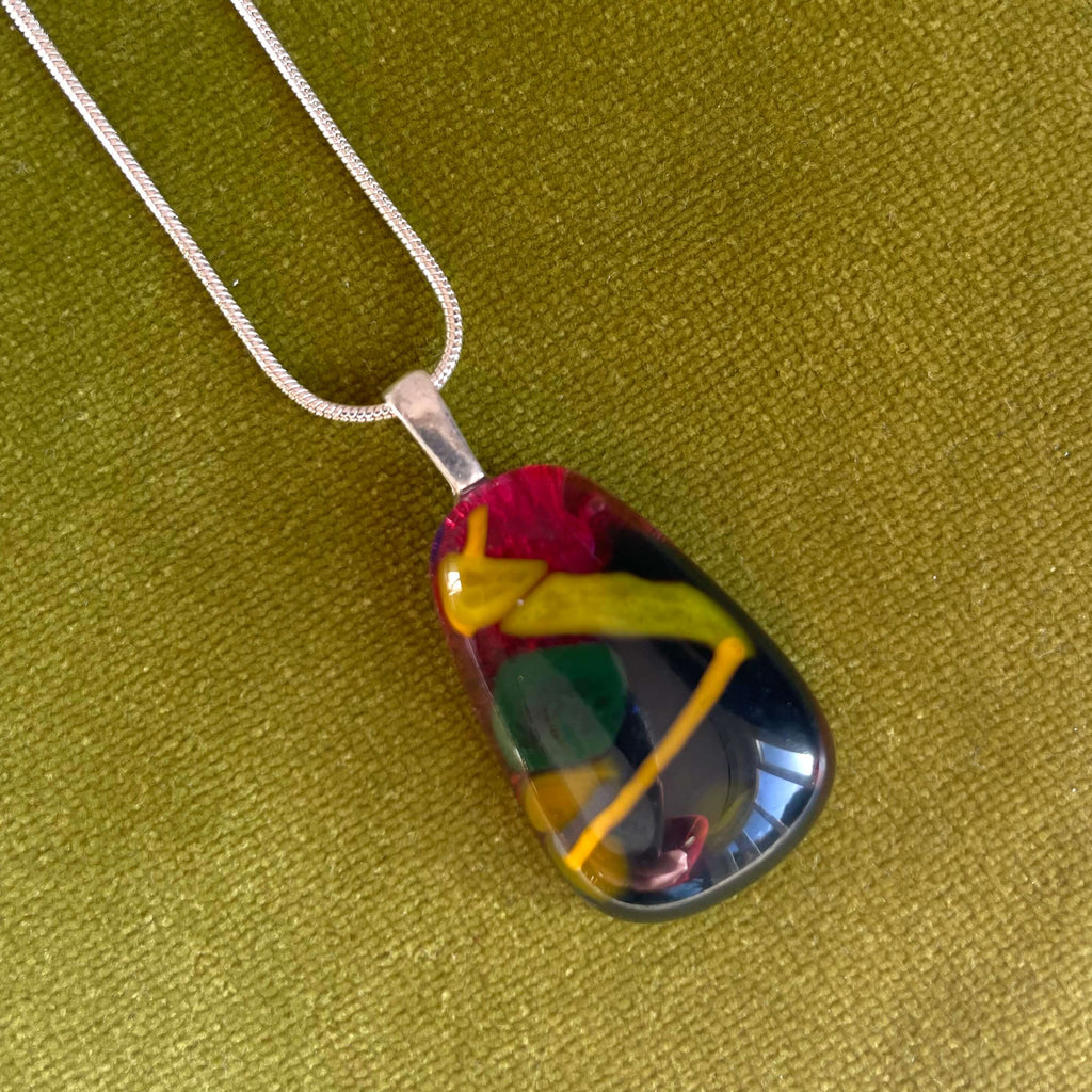  hand-crafted fused glass pendant. colourful fused glass, rich cherry red, yellow, mustard, green. on sterling silver snake chain, complete one-off, only one available, on green velvet background