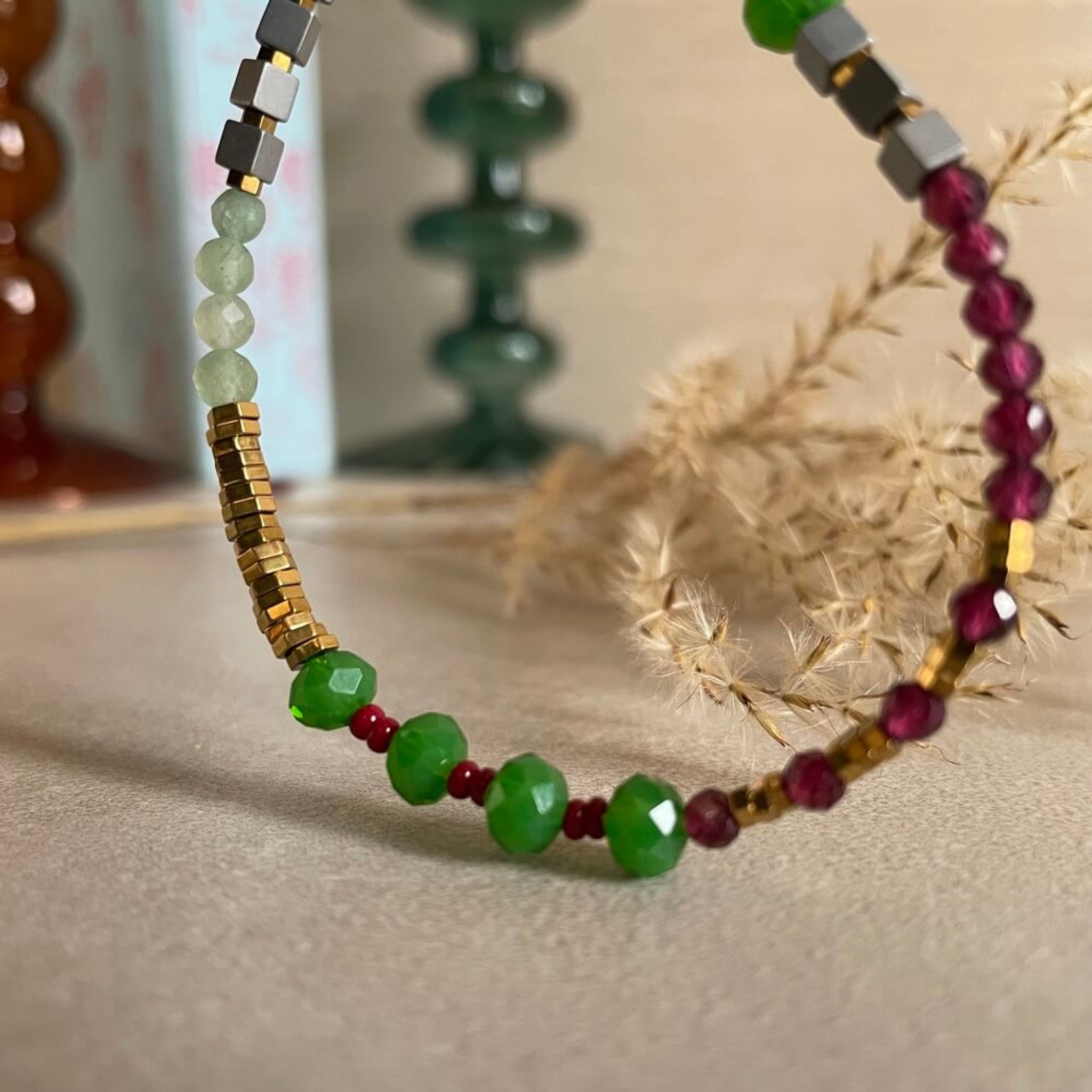 Beaded bracelet with green, red, and gold beads on a textured surface, green, pink, glass beads,  red garnet, golden hematite beads on 14k rolled gold  findings, 