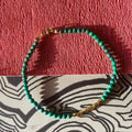 green malachite and gold hematite  beaded bracelet on a textured red and patterned surface, made with 14l rolled gold quality fixtures
