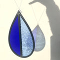 dark blue and light blue hanging stained glass, garden tree spinner or window sun catcher, hanging against a white background