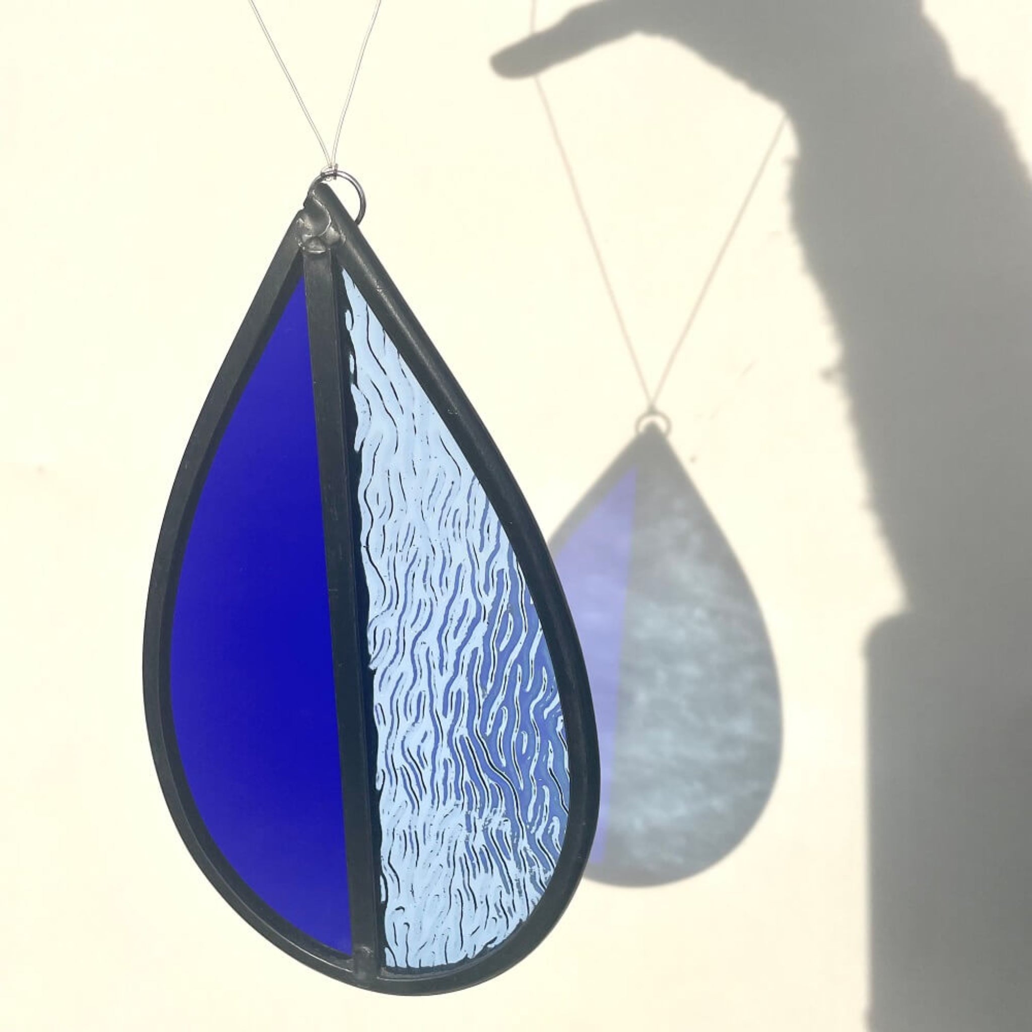 dark blue and light blue hanging stained glass, garden tree spinner or window sun catcher, hanging against a white background