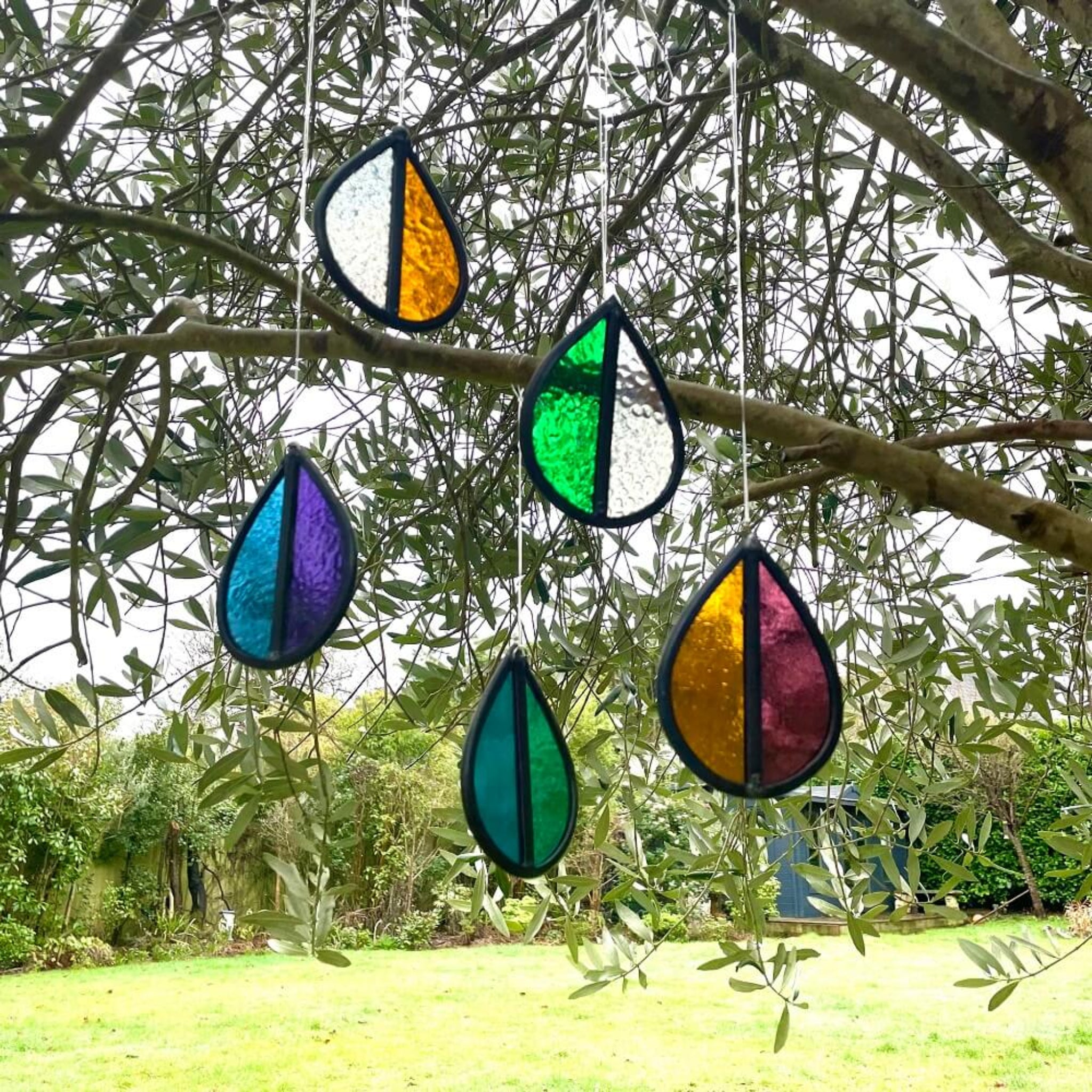Colorful stained glass teardrop shapes hanging from a tree