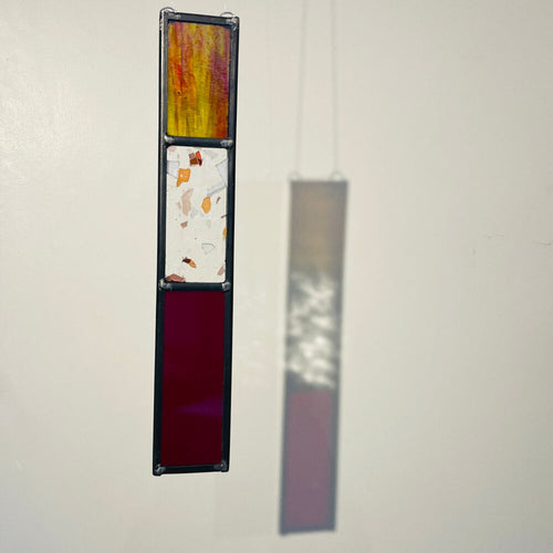 Decorative long rectangle, red stained glass garden tree spinner, in house sun catcher, hanging panel with 3 colourful stained glass sections on a plain background