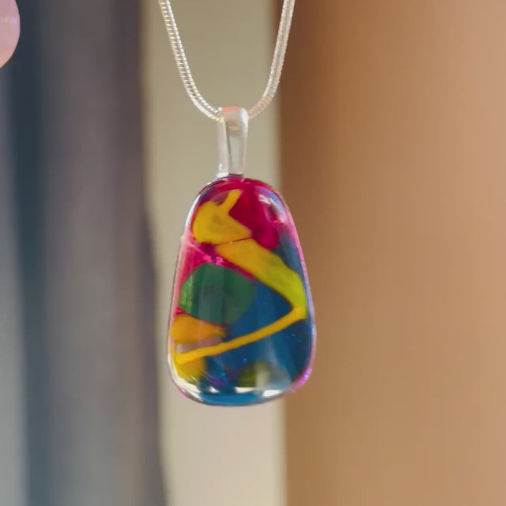 video of swinging hand-crafted fused glass pendant. colourful fused glass, rich cherry red, yellow, mustard, green. on sterling silver snake chain, complete one-off, only one available