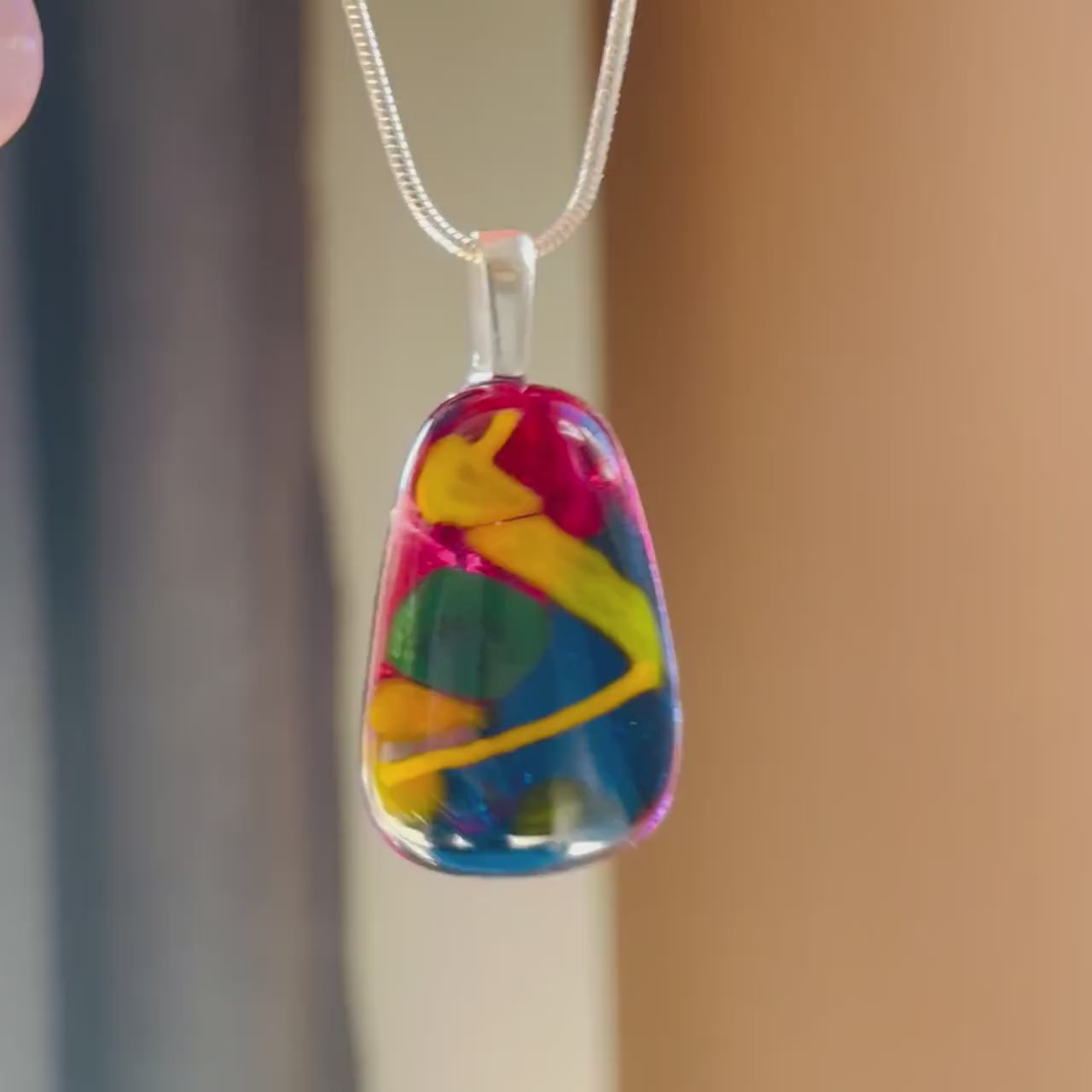 video of swinging hand-crafted fused glass pendant. colourful fused glass, rich cherry red, yellow, mustard, green. on sterling silver snake chain, complete one-off, only one available