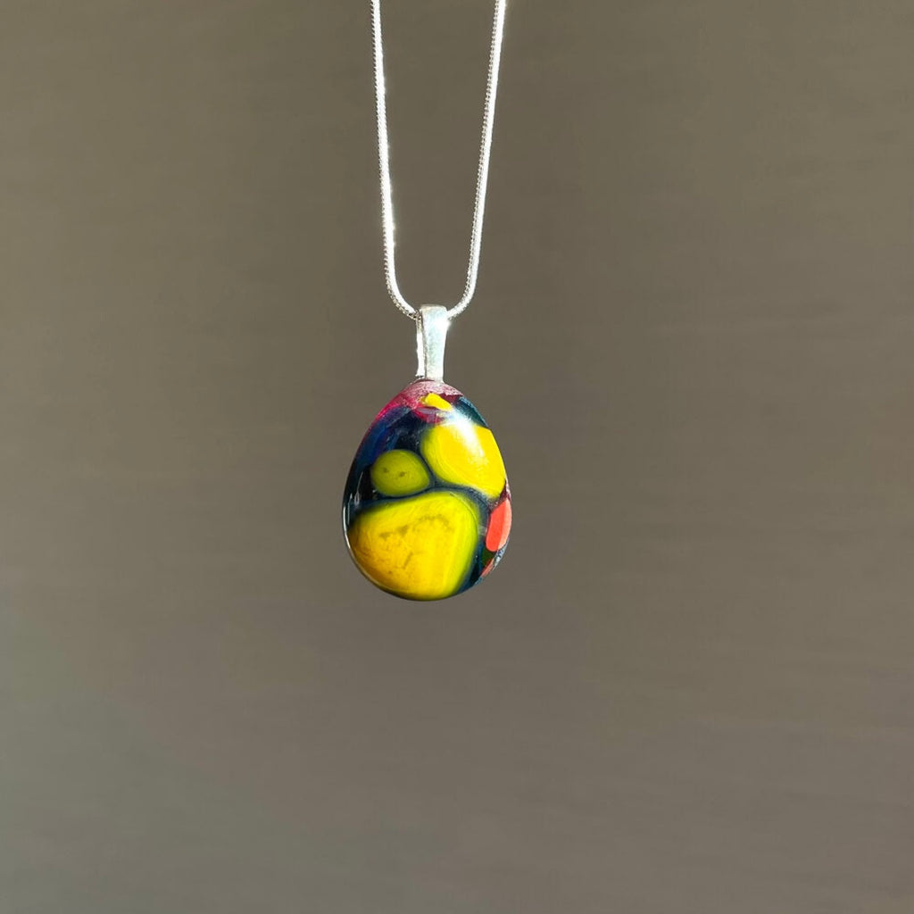  colorful fused glass art pendant, yellow, blue, pink fused glass, with sterling silver chain and bail, necklace against a earthy coloured background